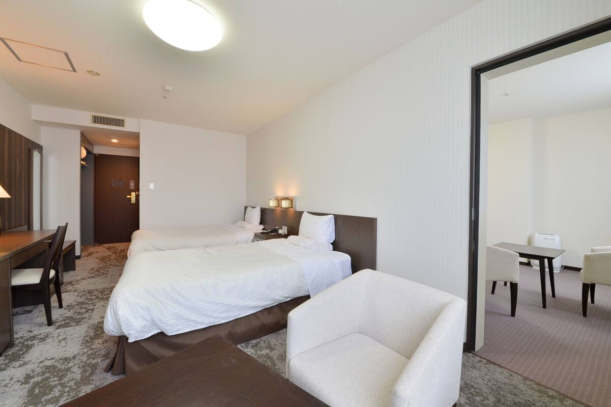 Een hotelkamer met twee bedden, een bureau, een stoel en een tafeltje.