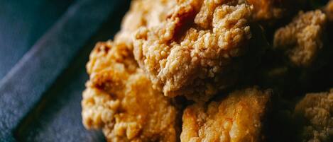 A close-up of fried chicken pieces on a dark plate.
