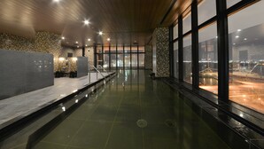 A modern indoor pool area with a clear view of the cityscape through large windows. - Hakodate Kokusai Hotel (Hakodate)