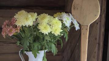 A white pitcher filled with yellow and pink flowers on a wooden table.