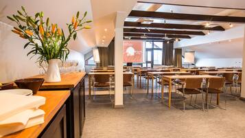 A modern conference room with tables and chairs, a whiteboard, and a projector screen.