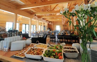 Montaje de bufé en un ambiente de madera con mesas, sillas y diferentes platos de comida.
