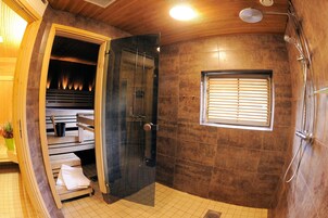 Un baño moderno con ducha envuelta en vidrio, bancos de madera y ventana con persianas.