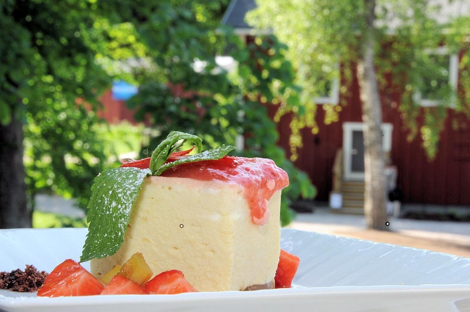 Un postre con fresas y hojas de menta sobre un plato blanco.