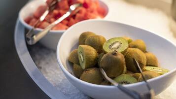 Two bowls of fruit on a tray with ice.