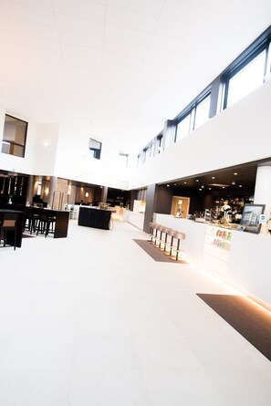 A spacious indoor area with a bar and seating area, featuring a modern design with a high ceiling and large windows. - Hotel Pommern (Mariehamn)