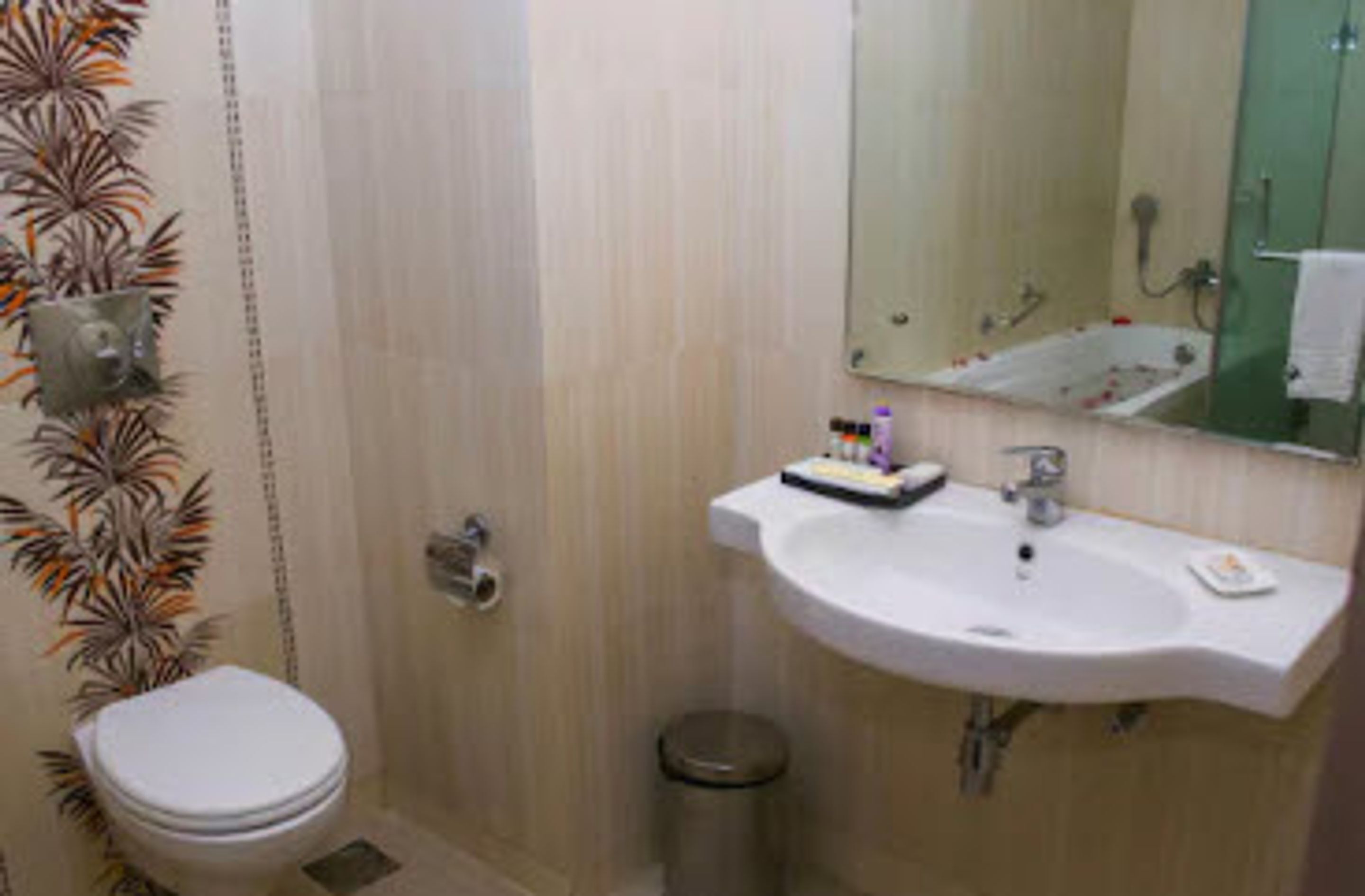 Un baño con inodoro, lavabo, espejo y ducha.