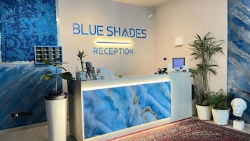 Un'area reception con un bancone in marmo, piante e opere d'arte.