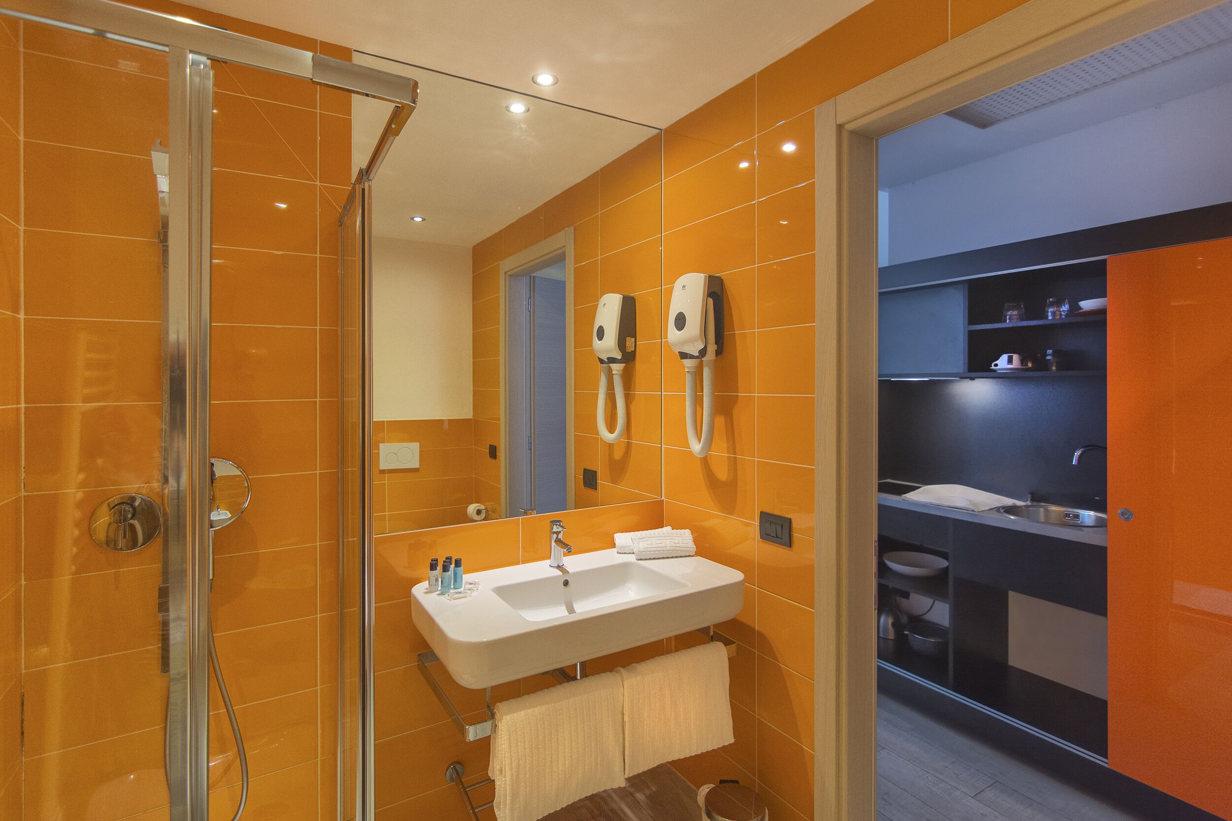 Un baño moderno con cabina de ducha de vidrio, un lavabo con espejo y un perchero para toallas.