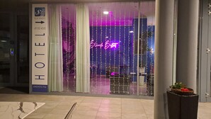 Entrada de hotel con un cartel que indica 'Blue-Shades' y un número de teléfono.