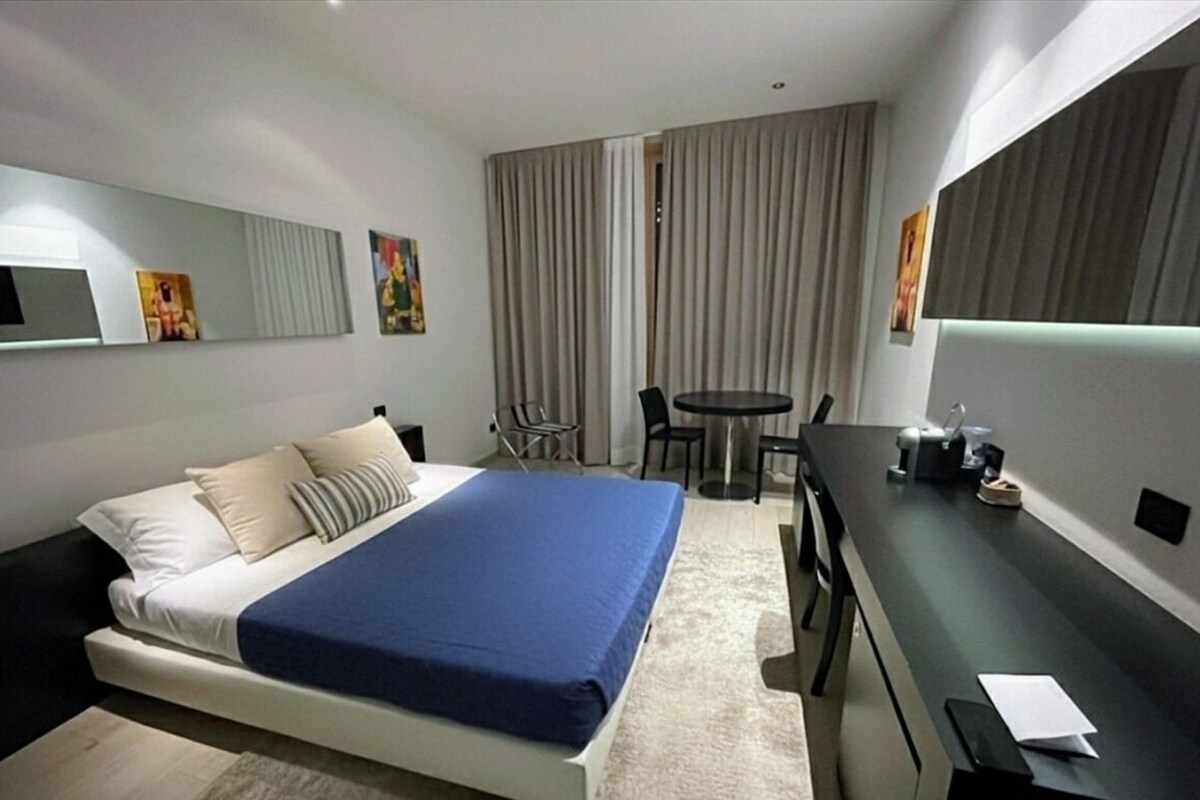 Una habitación de hotel con una cama, un escritorio, una silla y una mesita.