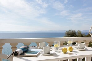 A table with a book, two cups, a glass of water, and lemons on a balcony overlooking the sea. - Apollon Apartments (West Mani)