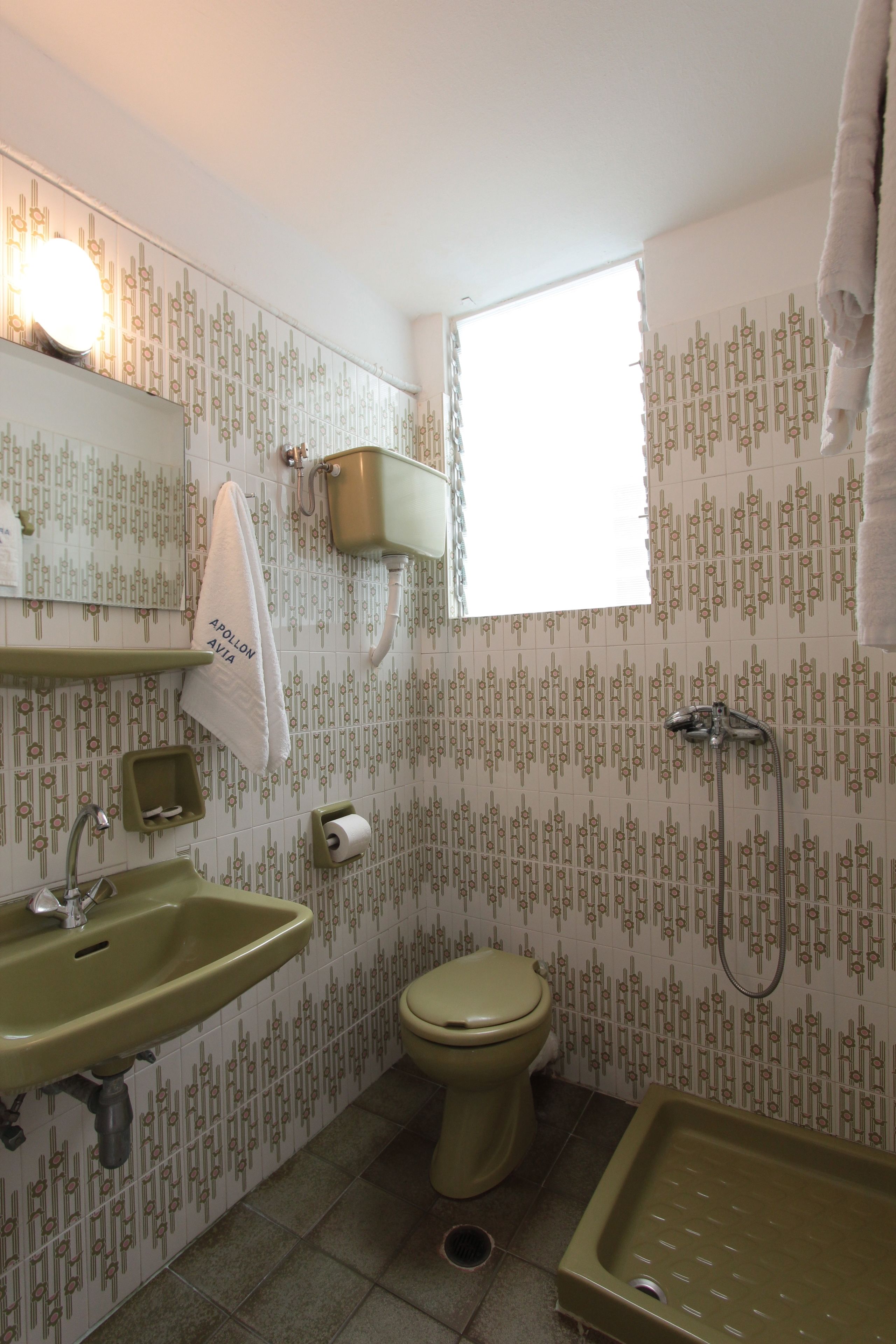 A compact bathroom with a sink, toilet, and shower.