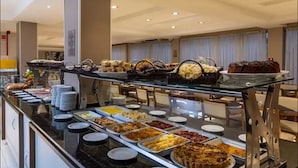 Un bufé con diferentes alimentos y un pastel sobre un mostrador de vidrio.