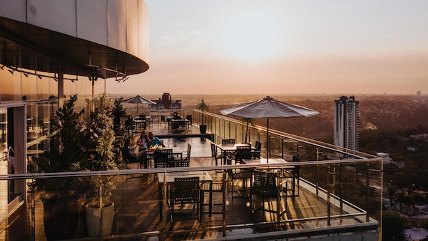 Una terraza en la azotea con mobiliario exterior, piscina y vistas a la ciudad.
