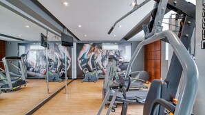 Un gimnasio con equipo de ejercicio, un espejo grande y un mural en la pared.