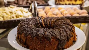 A chocolate bundt cake with chocolate sprinkles on a white plate.