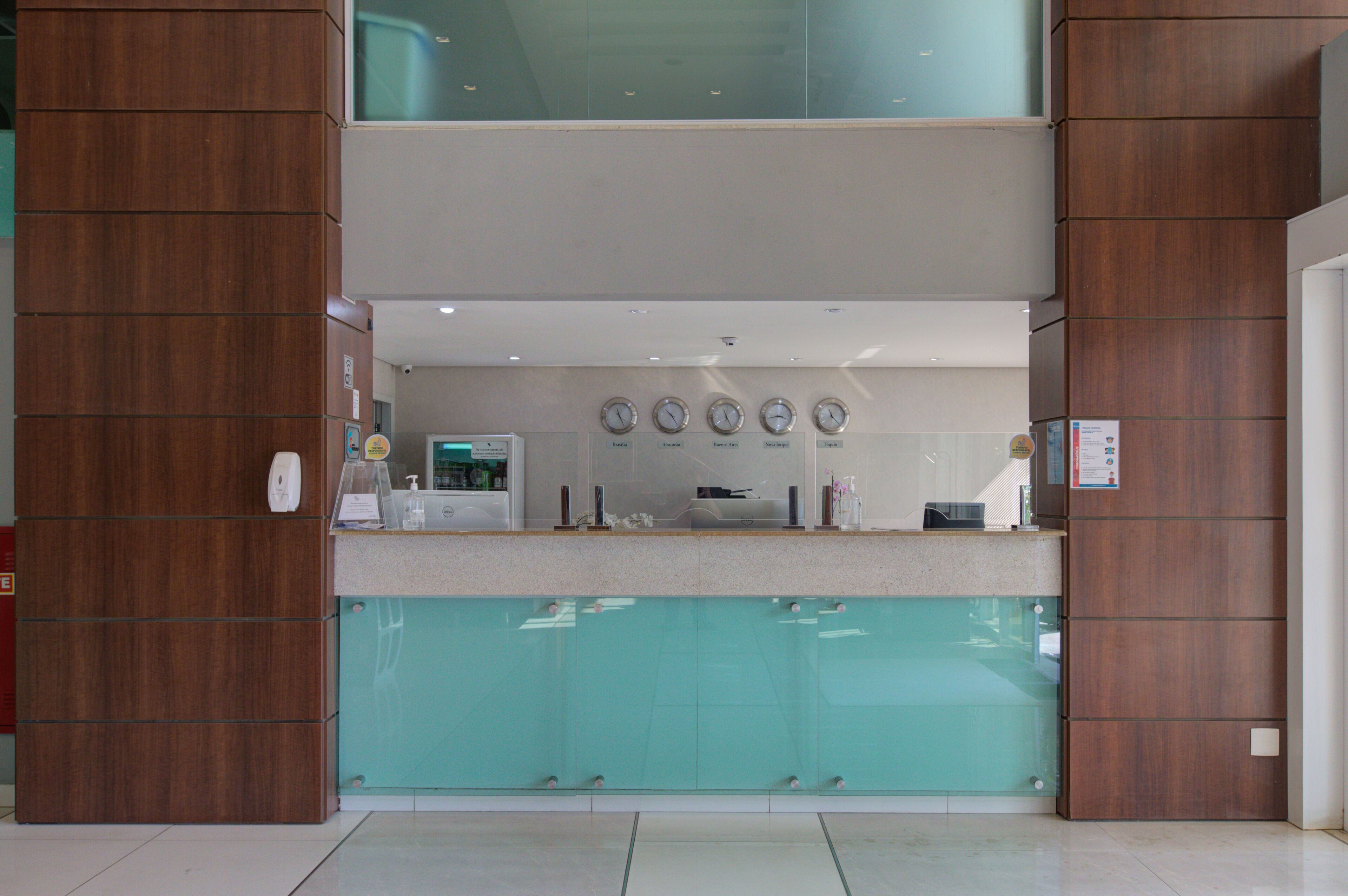 A reception area with a wooden reception desk, a glass partition, and a wall-mounted clock.