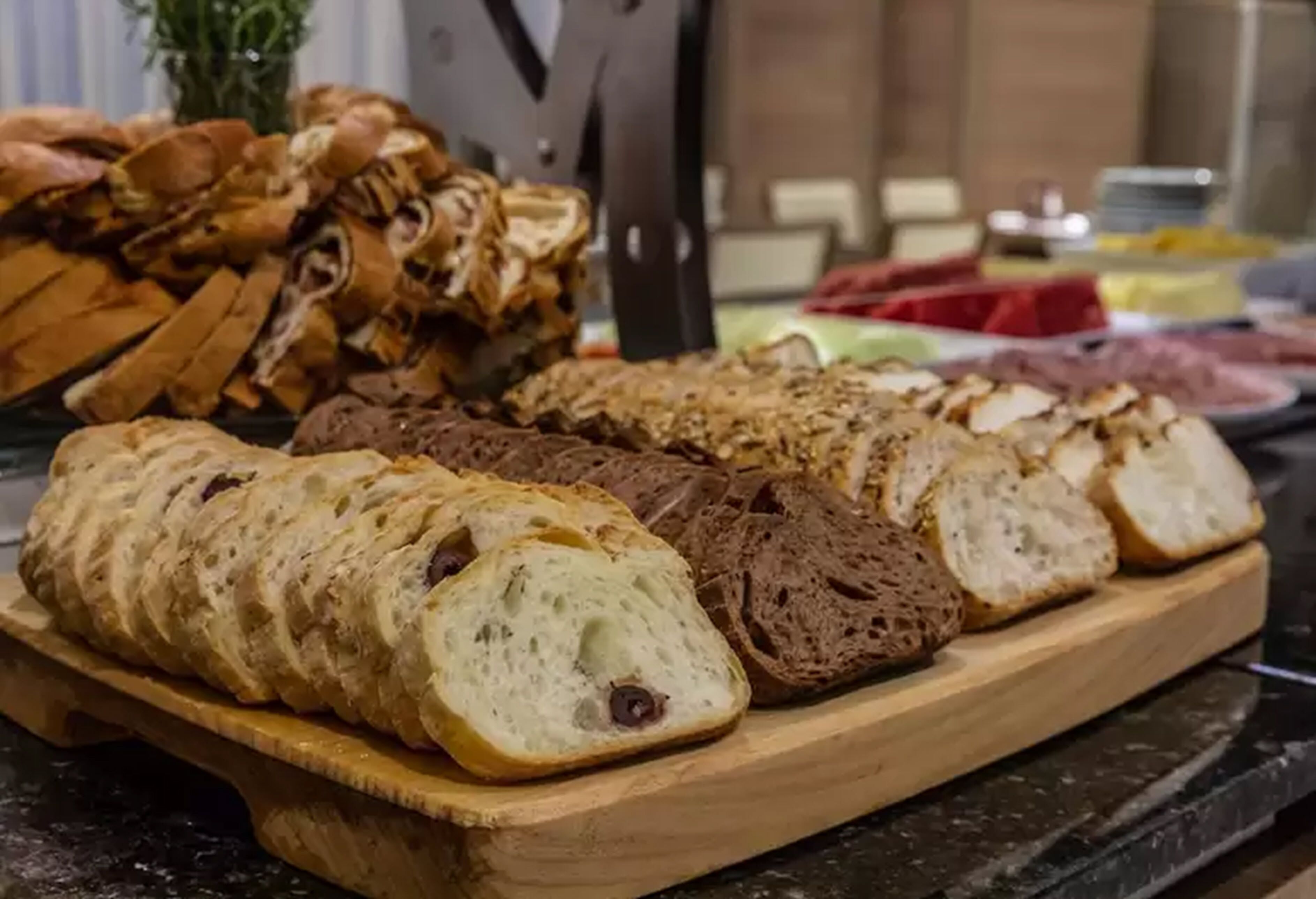 Een houten plank met verschillende soorten brood, zowel in plakken als hele broden.