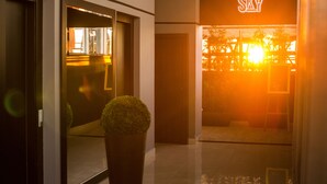 Entrada de un edificio moderno con un letrero que dice 'SKY', una planta en maceta y una puerta de cristal que refleja el interior.