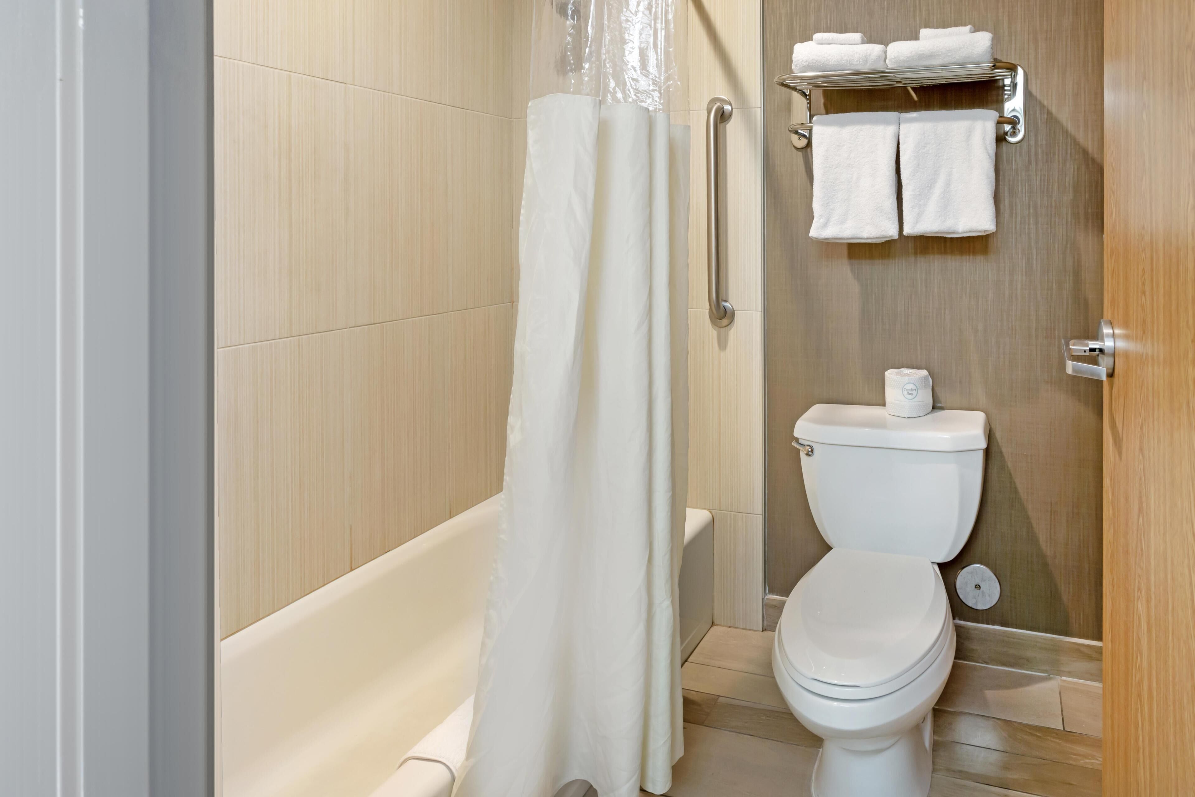 Un baño con bañera, inodoro y cortina de ducha.