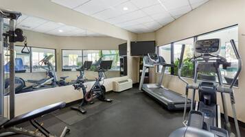 A gym with exercise equipment, a TV, and large windows.
