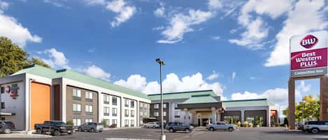 A Best Western Plus hotel with multiple buildings, a parking lot, and a clear sky.