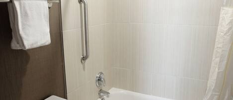 Un baño moderno con inodoro, ducha con barra de apoyo y bañera.
