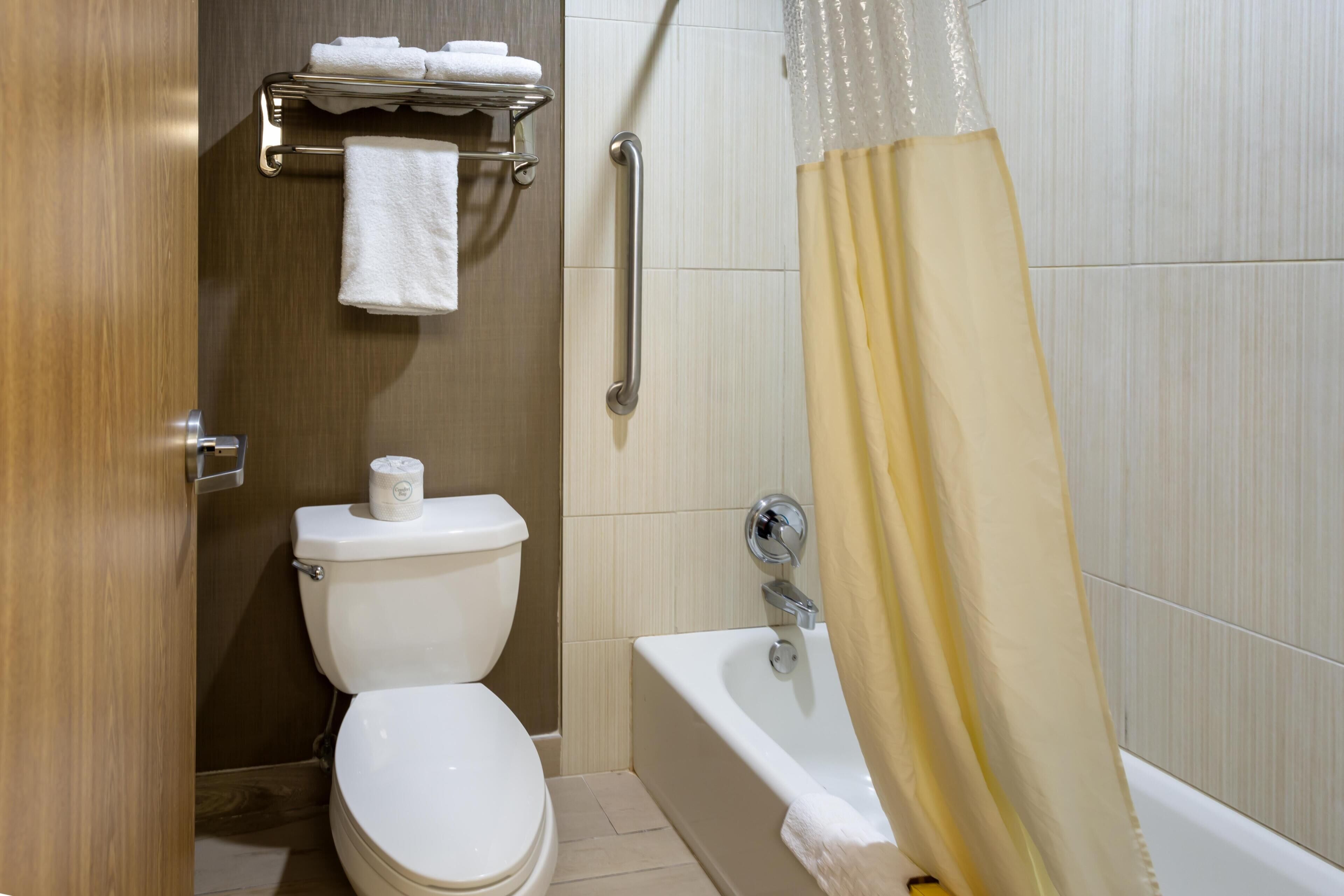 Ein Badezimmer mit Toilette, Handtuchhalter, Duschvorhang und Badewanne.