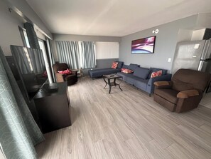 A modern living room with a sofa, armchair, and a coffee table. - Sand Castle Motel (Daytona Beach Shores)