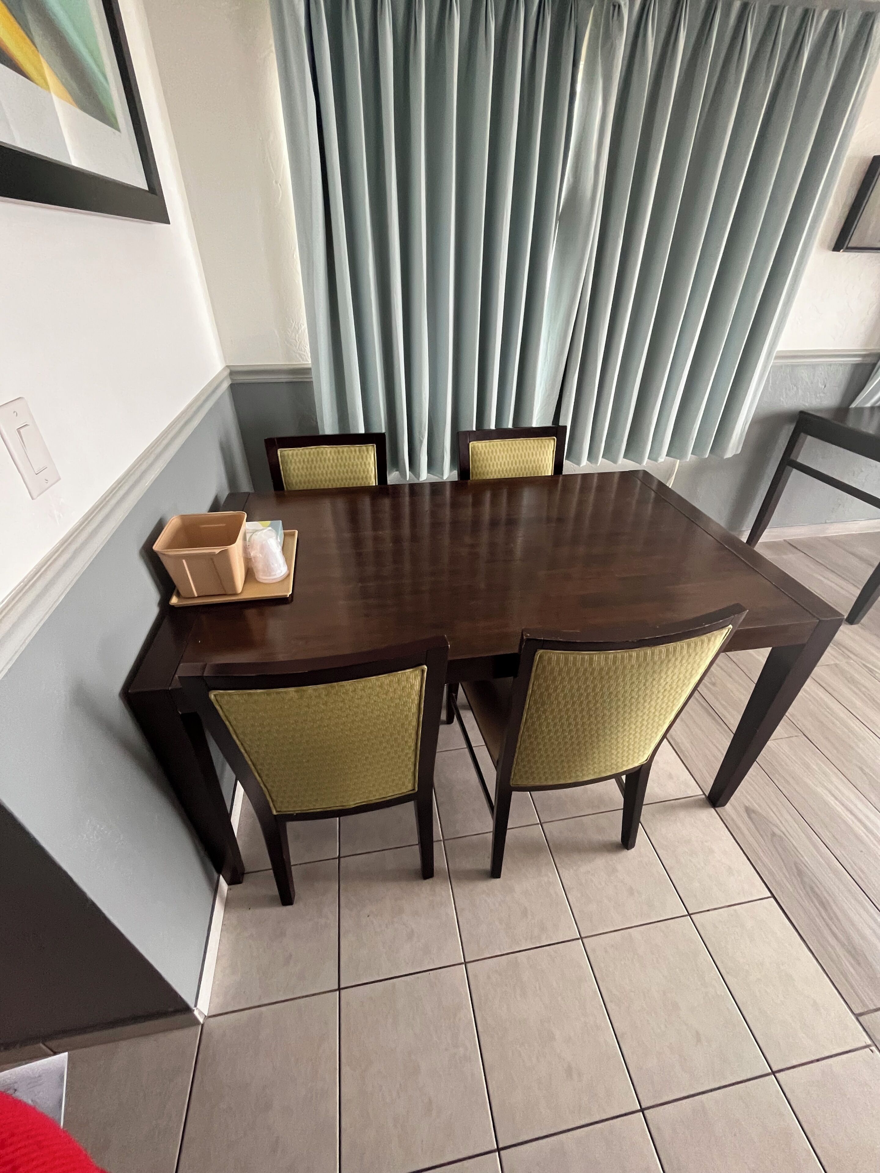 Un comedor con una mesa rectangular, cuatro sillas y un juego de cortinas.