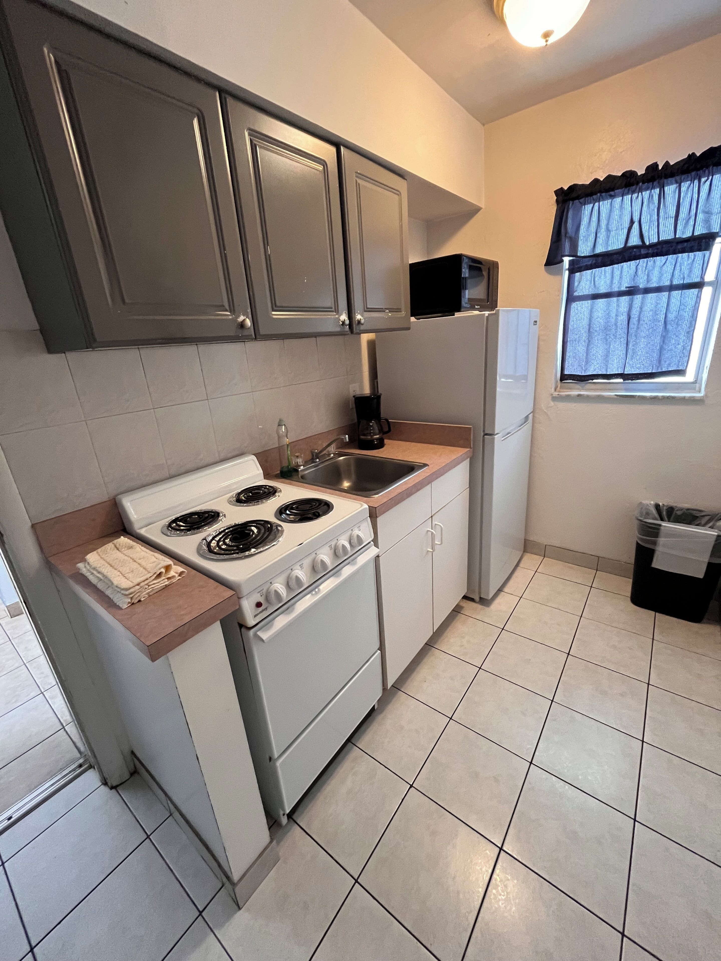 Una cocina compacta con estufa, lavabo y refrigerador.