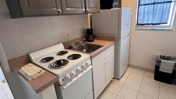 Una cocina compacta con estufa, lavabo y refrigerador.
