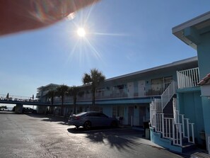 A residential building with a balcony, a car parked in front, and a clear sky. - Sand Castle Motel (Daytona Beach Shores)