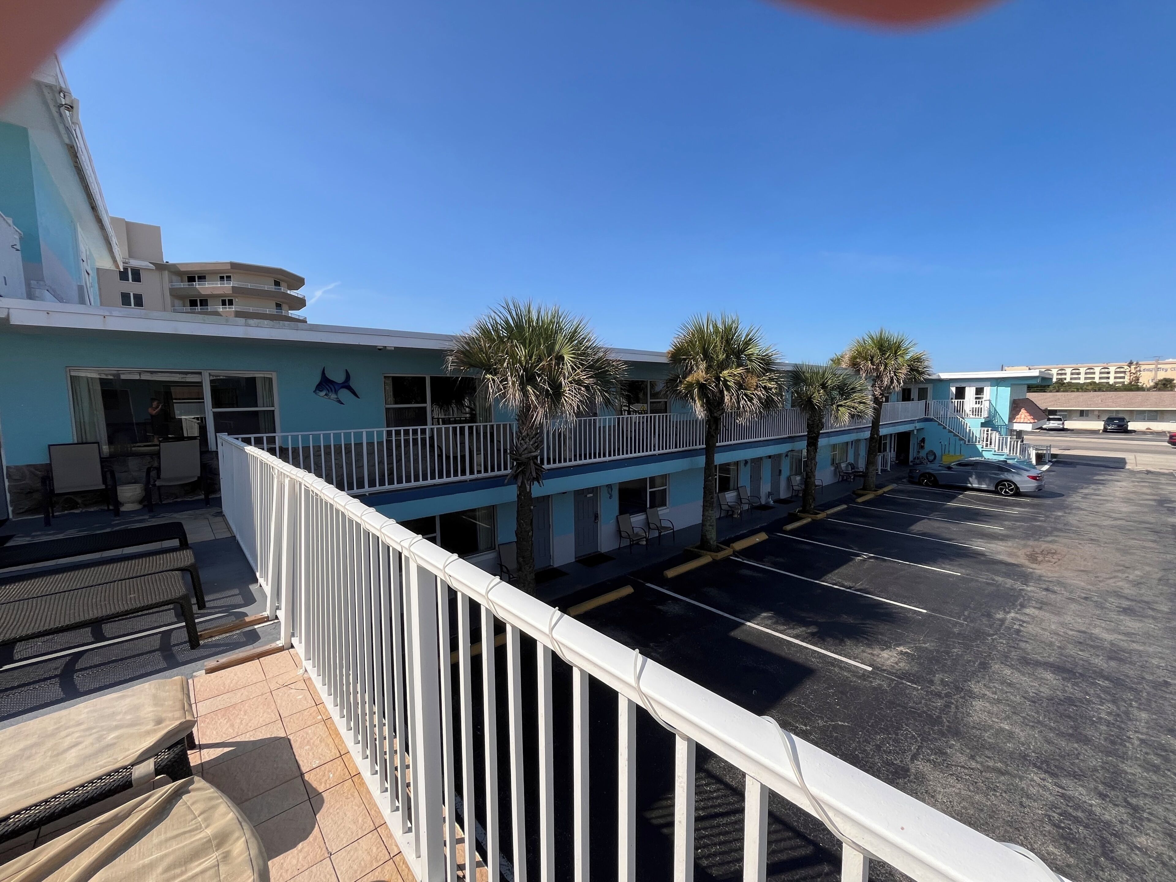 A hotel with a pool area, outdoor seating, and a parking lot.