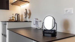 A makeup station with a mirror and a towel labeled "Makeup" on a countertop. - Hotel Rigas (Milos)