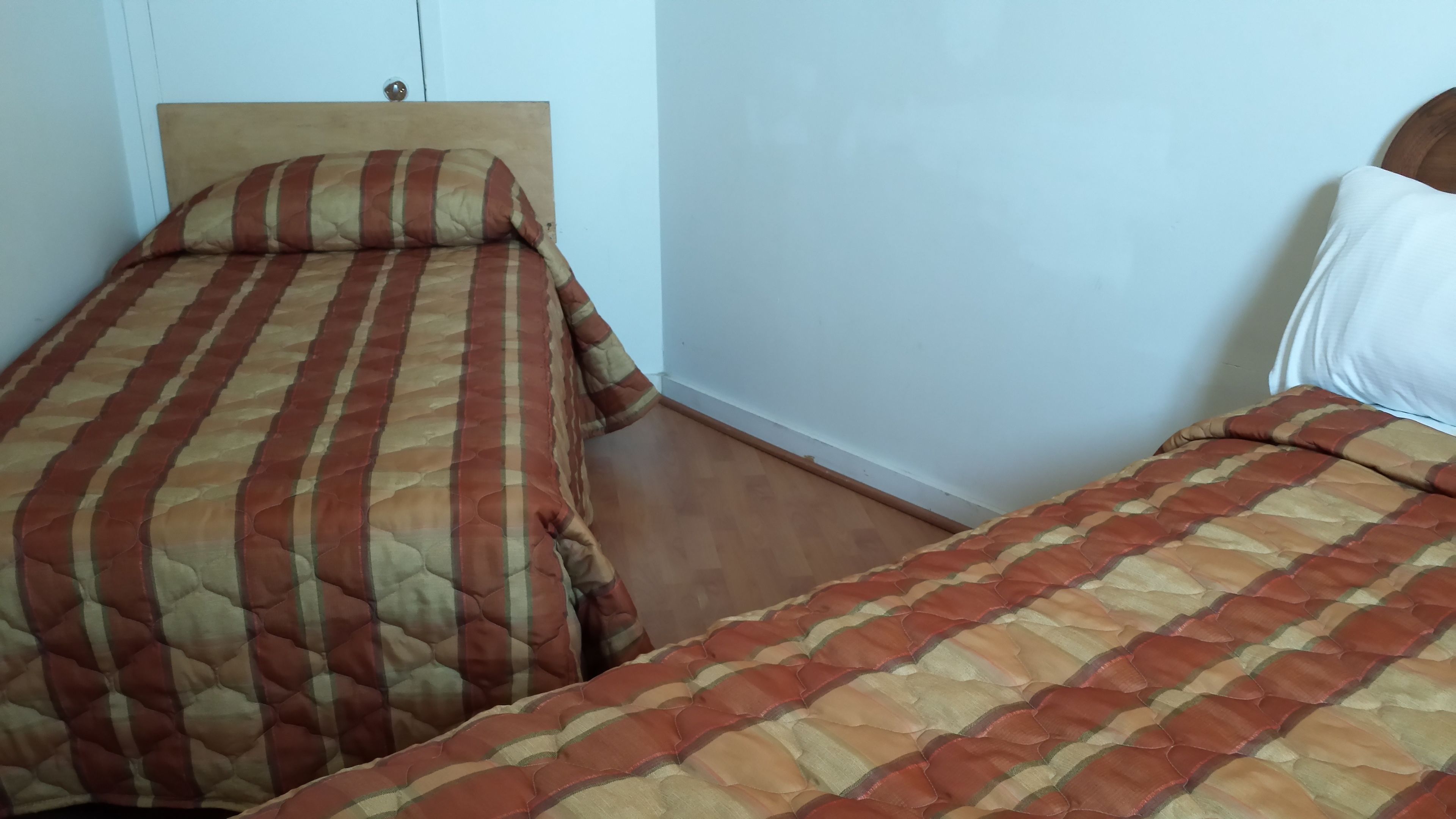 Une chambre avec deux lits, chacun étant équipé de draps à rayures.