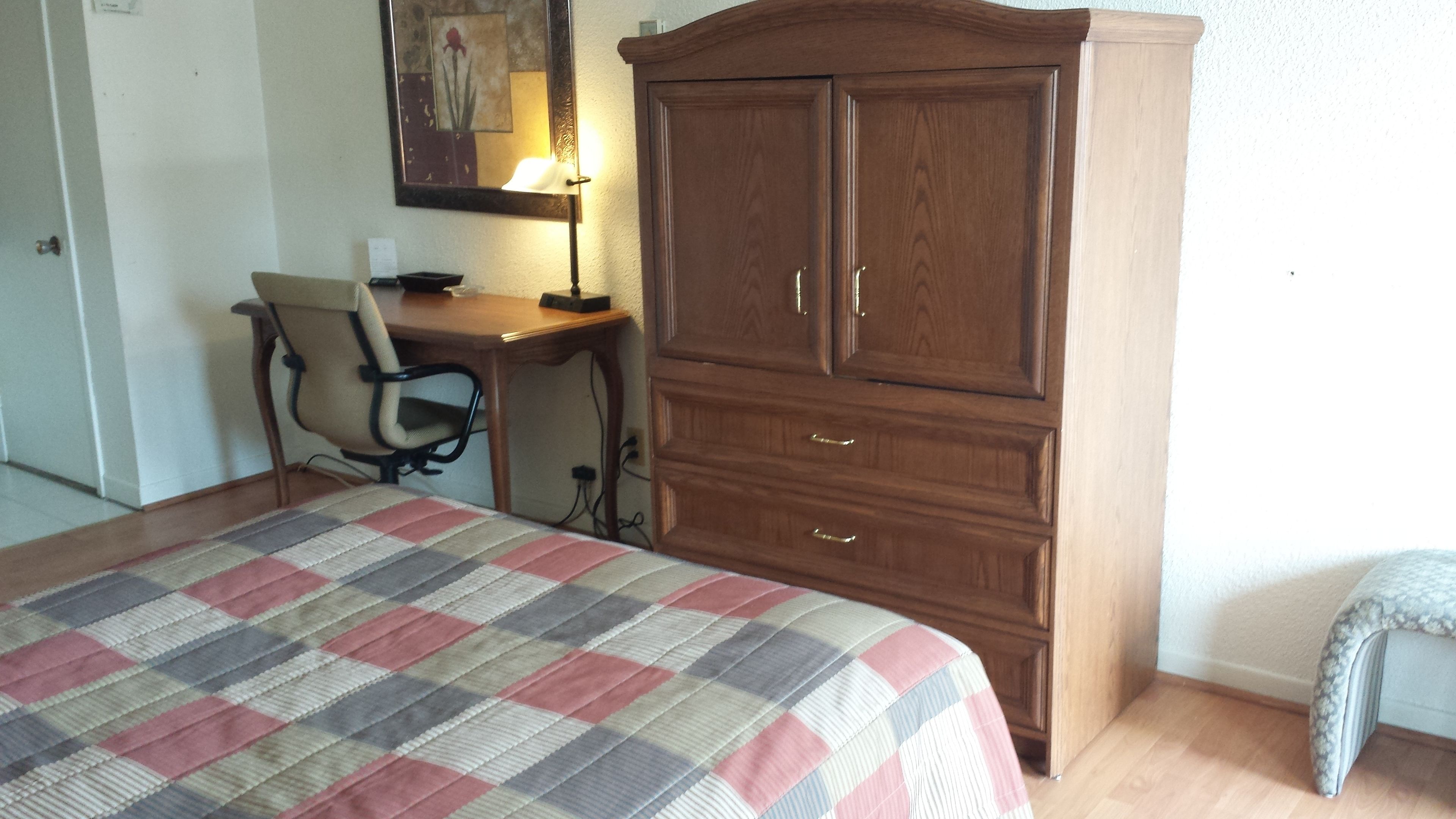 Une chambre à coucher comprenant un lit, un bureau, une chaise et une armoire.