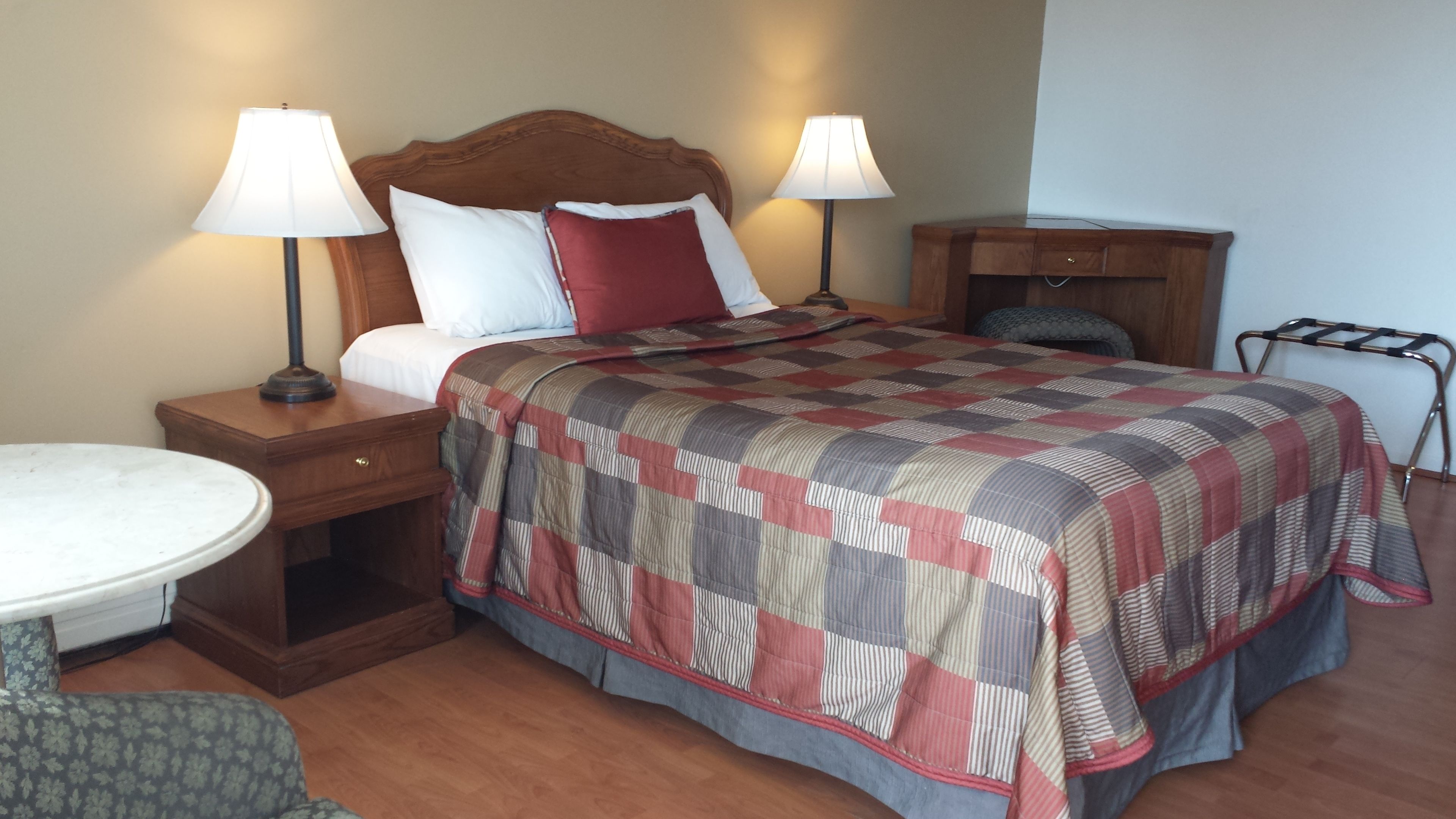A hotel room with a large bed, two bedside tables with lamps, a small round table, and a chair.