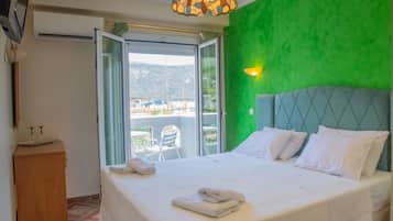 A hotel room with a bed, a green wall, and a view of the outside.