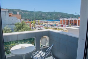 A balcony with a table and chairs, a view of a parking lot, and buildings in the background. - Astoria Hotel (Igoumenitsa)