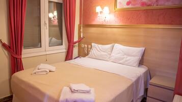 A hotel room with a bed, a nightstand, a lamp, and a window with curtains.