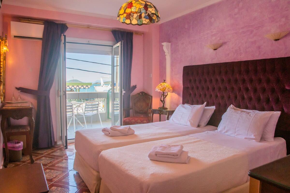 A hotel room with two beds, a balcony, and a view of the sea.
