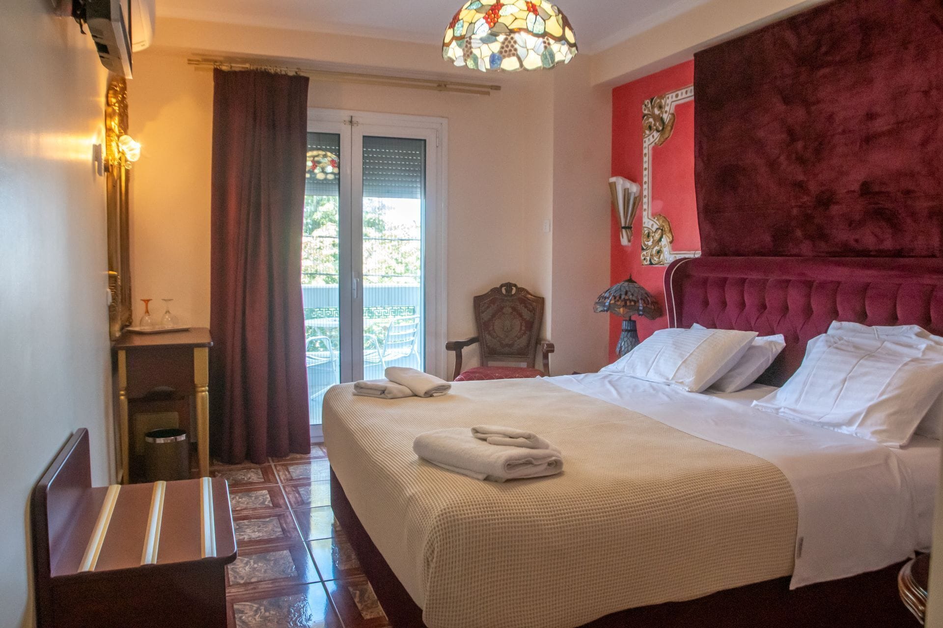 A hotel room with a bed, a chair, a small table, and a window with curtains.