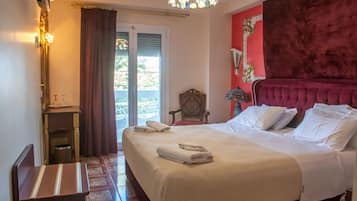 A hotel room with a bed, a chair, a small table, and a window with curtains.