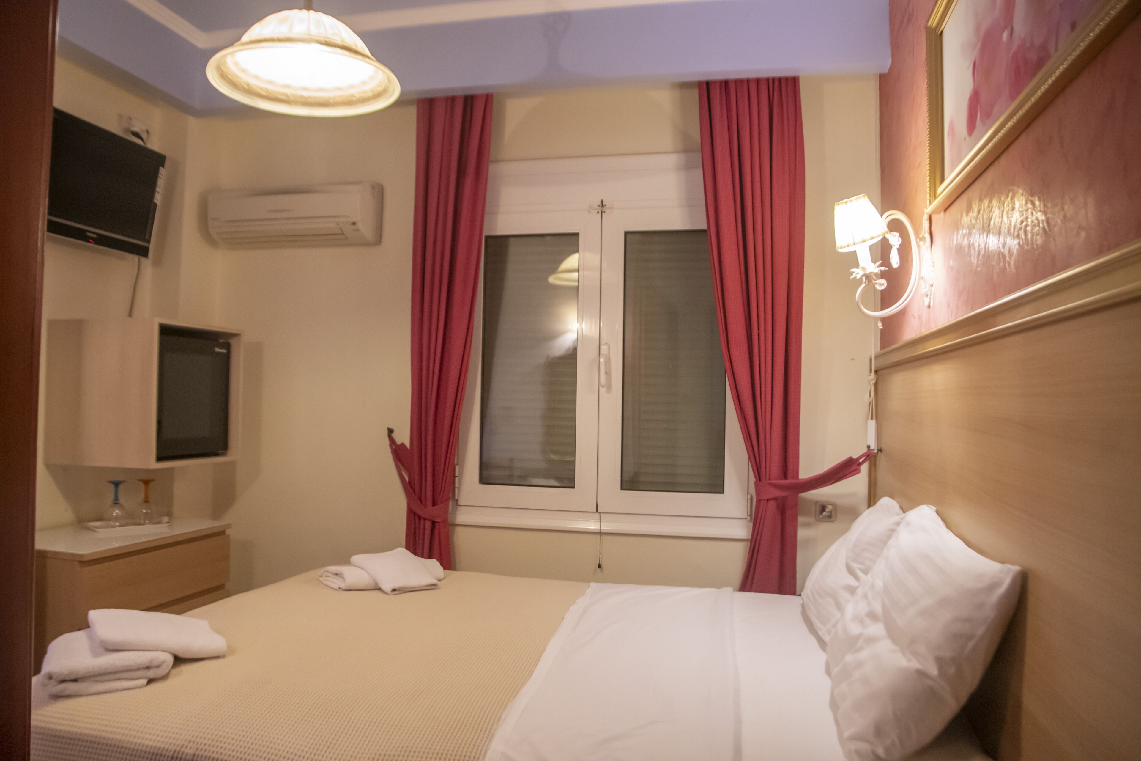 Ein Hotelzimmer mit Bett, Fernseher, Klimaanlage und einem Vorhangfenster.