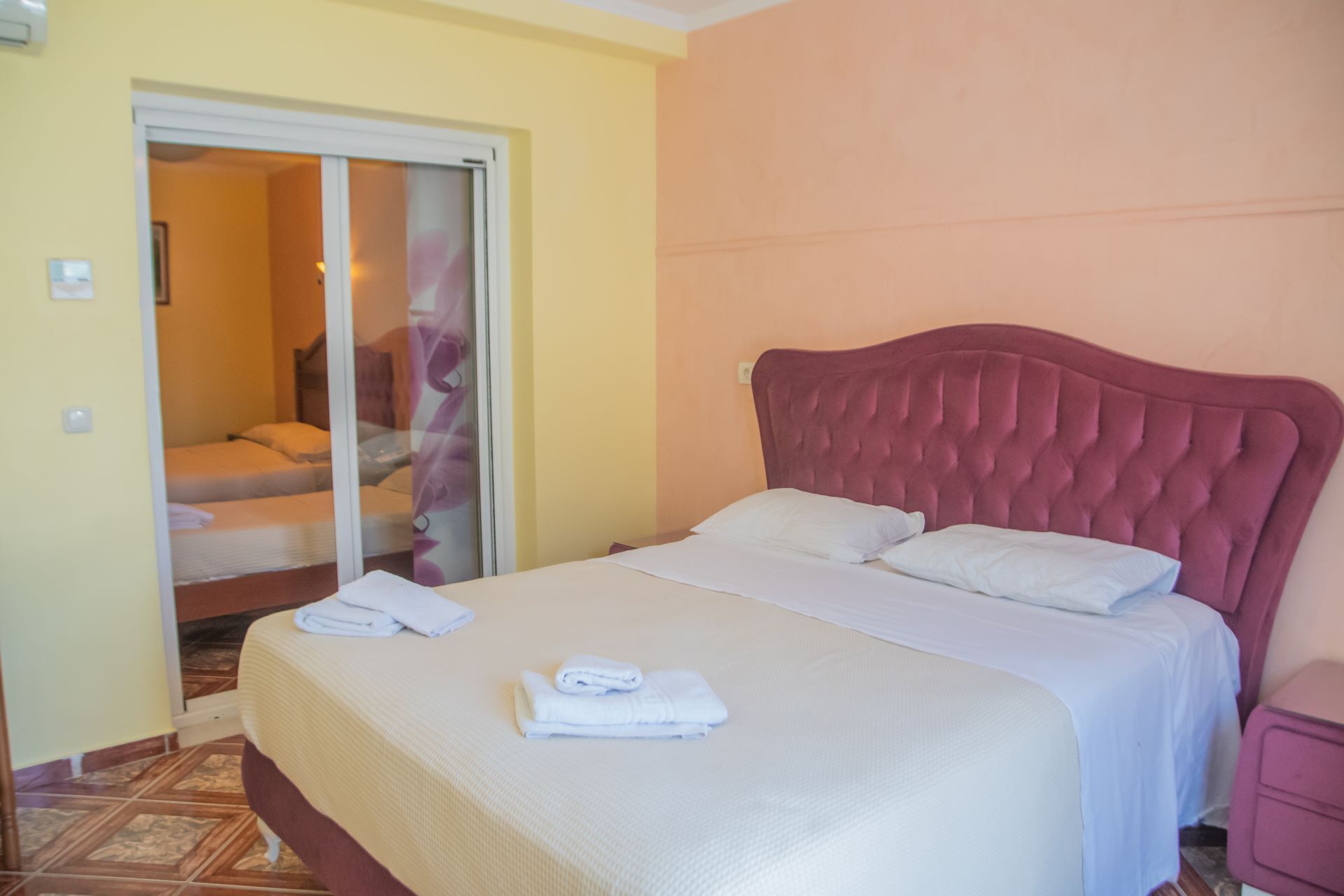 A hotel room with a bed, a bathroom with a shower, and a door leading to another room.