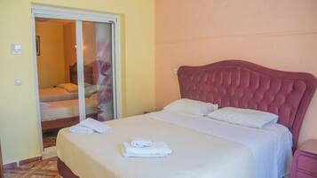 A hotel room with a bed, a bathroom with a shower, and a door leading to another room.