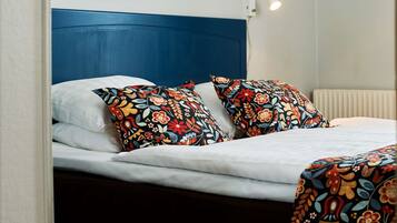 A bed with a blue headboard, white bedding, and colorful floral-patterned pillows.