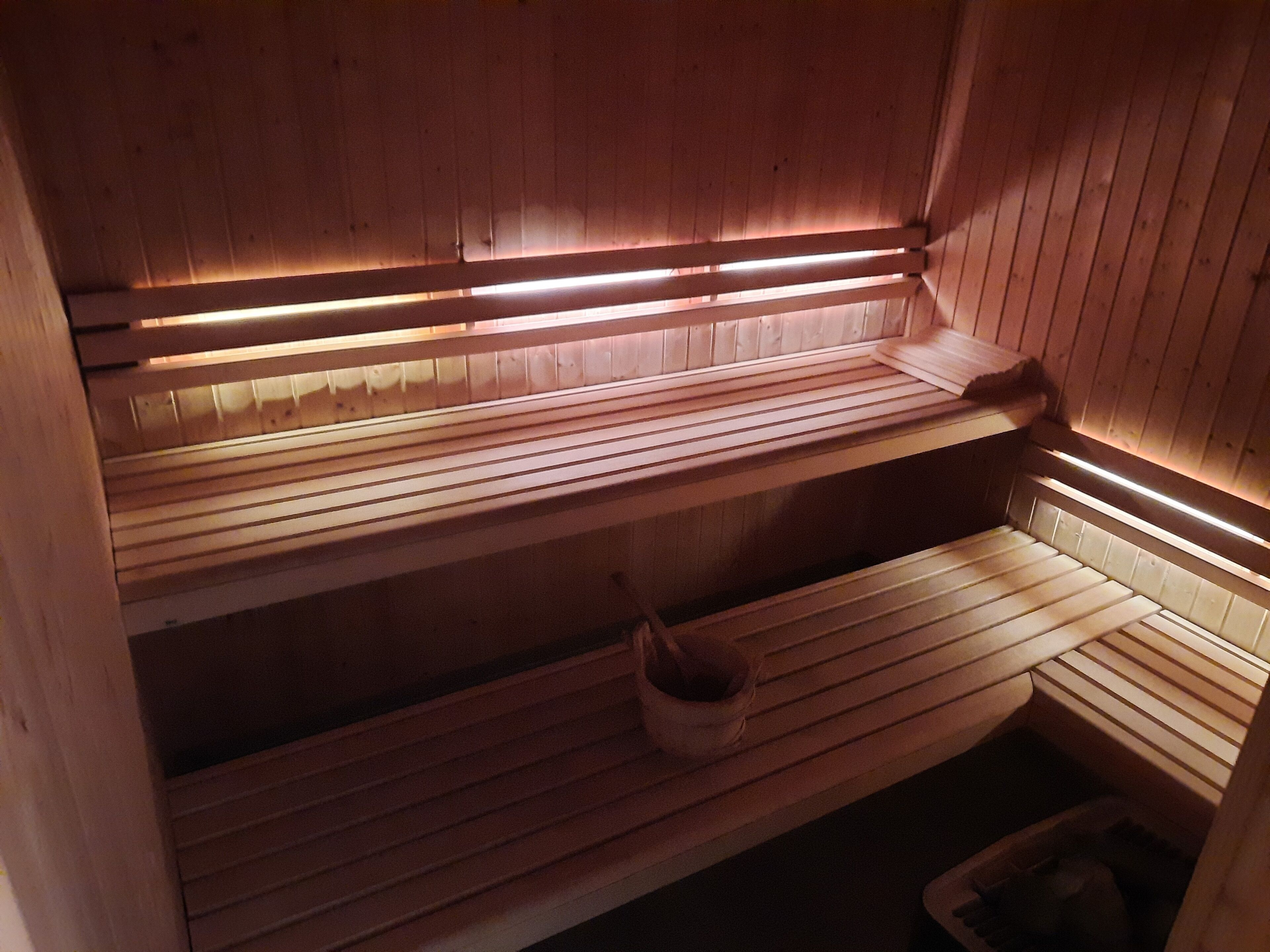 Eine Holzsauna mit Bänken und einem Eimer.